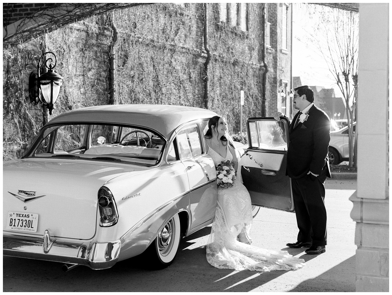 Portrait of a bride and groom looking at eachother the groom is helping the bride out of a classic cadilac car.